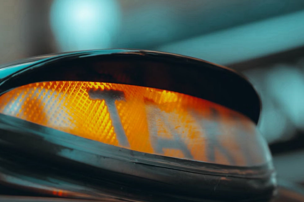 Close-up of a car’s amber side marker light glowing against a blurred teal background.