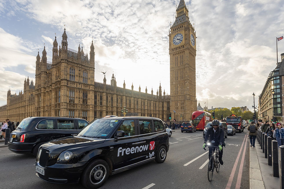 Big Ben and the Houses of Parliament over busy London traffic, with a Freenow taxi and a cyclist in the foreground.