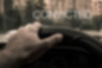 Hand gripping steering wheel with CONVICTED over blurred city buildings.