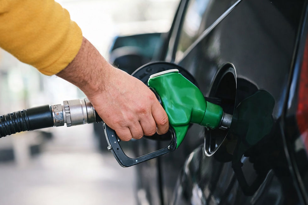 Hand in a yellow sleeve fuels a black car with a green gas pump. Close-up shot with a blurred background.