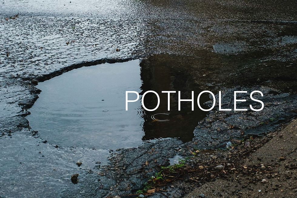 Wet asphalt road with a large pothole filled with water. The word "POTHOLES" is written in white text over the image.