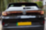 Black taxi speeding through a city at night, driver visible through the window, neon lights streaking in motion blur.