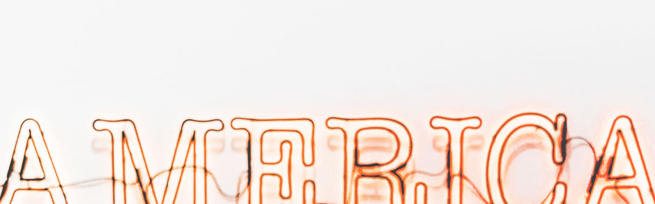Woman gazing at the neon sign which says AMERICA. Photography. My Site 1
