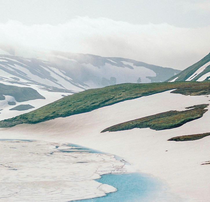 Snowy mountain range with patches of green vegetation