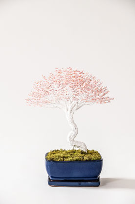 A bonsai tree with a white trunk and pink tiny origami swans as leaves
