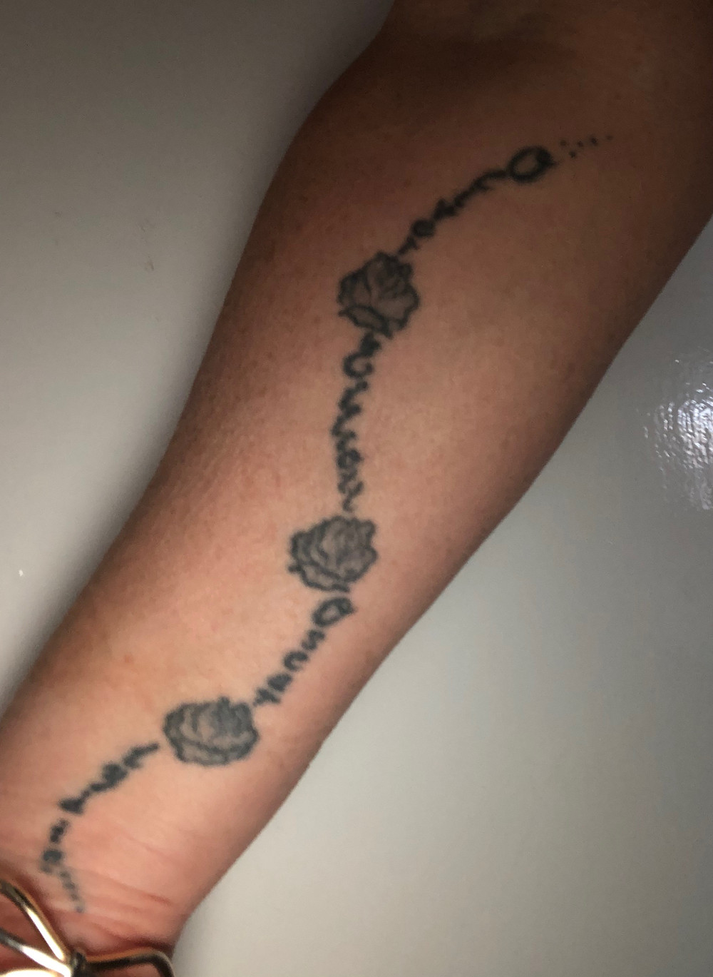 A tattoo with four names and four flowers