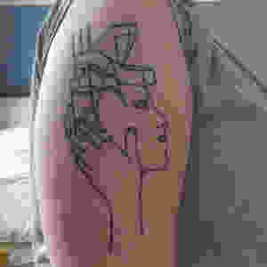 Tattoo on an arm of a face coming out of a building