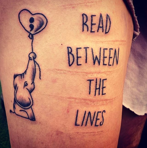 A tattoo saying Read Between The Lines. Also some self harming scars.