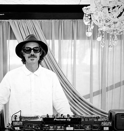 Tom McGrath behind the DJ decks in a black-and-white portrait
