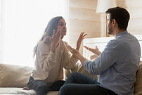 Angry young couple sit on couch in living room having family fight or quarrel suffer from