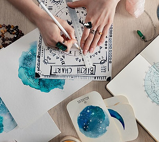 Top-down view of hands creating a birth chart