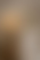 Détail d'une chambre à coucher zen avec une suspension en rotin tressé diffusant une lumière chaude sur un mur texturé beige. Table de chevet en bois massif et linge de lit blanc pour une ambiance Slow Déco et Feng Shui.