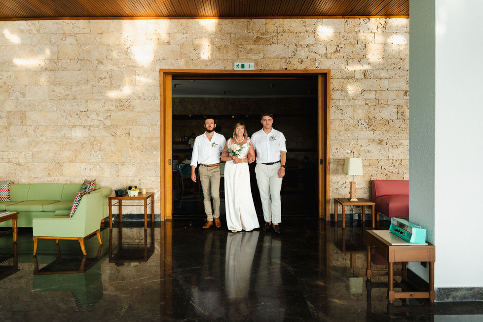 Three people standing in a warmly lit room in Skiathos.