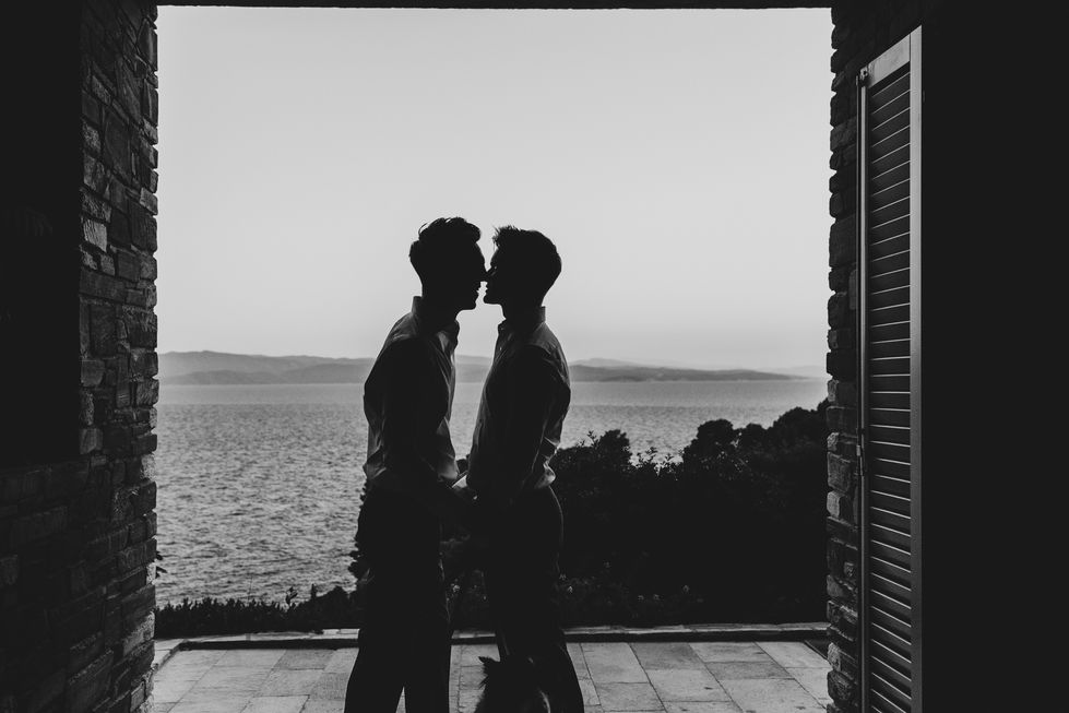 Silhouetted couple standing by the sea at sunset in Skiathos.