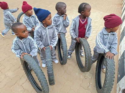 Young children in red hats playing together outdoors at Victoria's Children