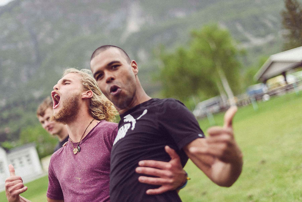 Auf dem Bild sind drei junge Männer zu sehen. Der hintere Junge ist kaum zu erkennen. Die beiden jungen Männer um Vordergrund umarmen sich freundschaftlich und grölen. Ihr Team habt bei den Lenggrieser Highlandgames gewonnen. Sie freuen sich sehr. Es ist ein sehr emotionales Bild.
