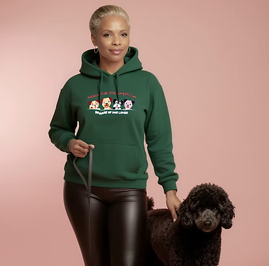 Woman wearing a green “Merch for Dog Lovers” hoodie featuring cartoon dog designs, posing with a black poodle against a pink background.