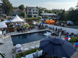 Backyard summer party with pool, guests, tents, and bounce house—expert outdoor event setup for family-friendly celebration near waterfront homes.
