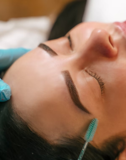 Close-up of a client at Le Chalan Nail Spa with freshly shaped, defined eyebrows being gently brushed with a spoolie.