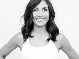 FutureFLEX trainer Santana with shoulder length black wavy hair, white top, hands on hips, smiling at the camera