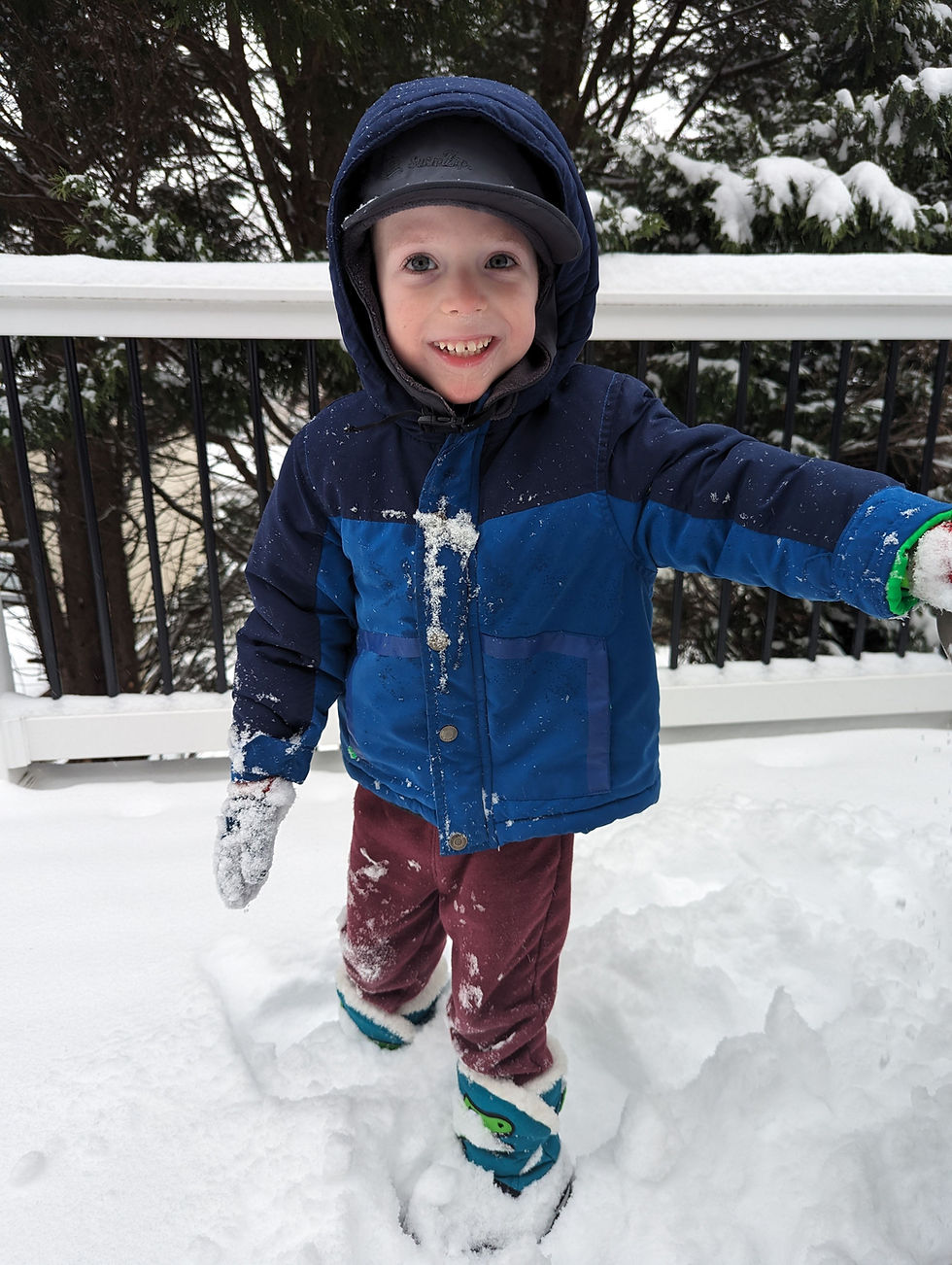 Smiling child in a blue jacket standing in snow
