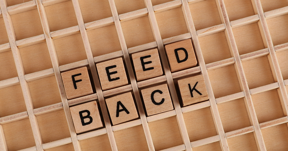 Wooden letters spell "FEEDBACK" on a wooden grid background