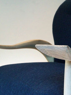 Blue chair with curved wooden armrests as part of hand made nature inspired furniture