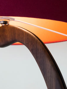 Curved wooden lamp close up with illuminated copper shade as part of hand made nature inspired furniture