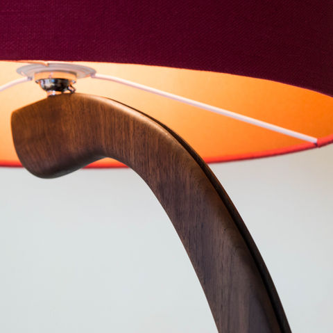 Curved wooden lamp close up with illuminated copper shade as part of hand made nature inspired furniture
