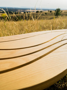Wavy wooden bench in a grassy landscape as part of hand made nature inspired furniture