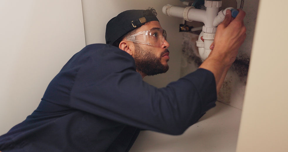 plumber under the sink looking at a pipe