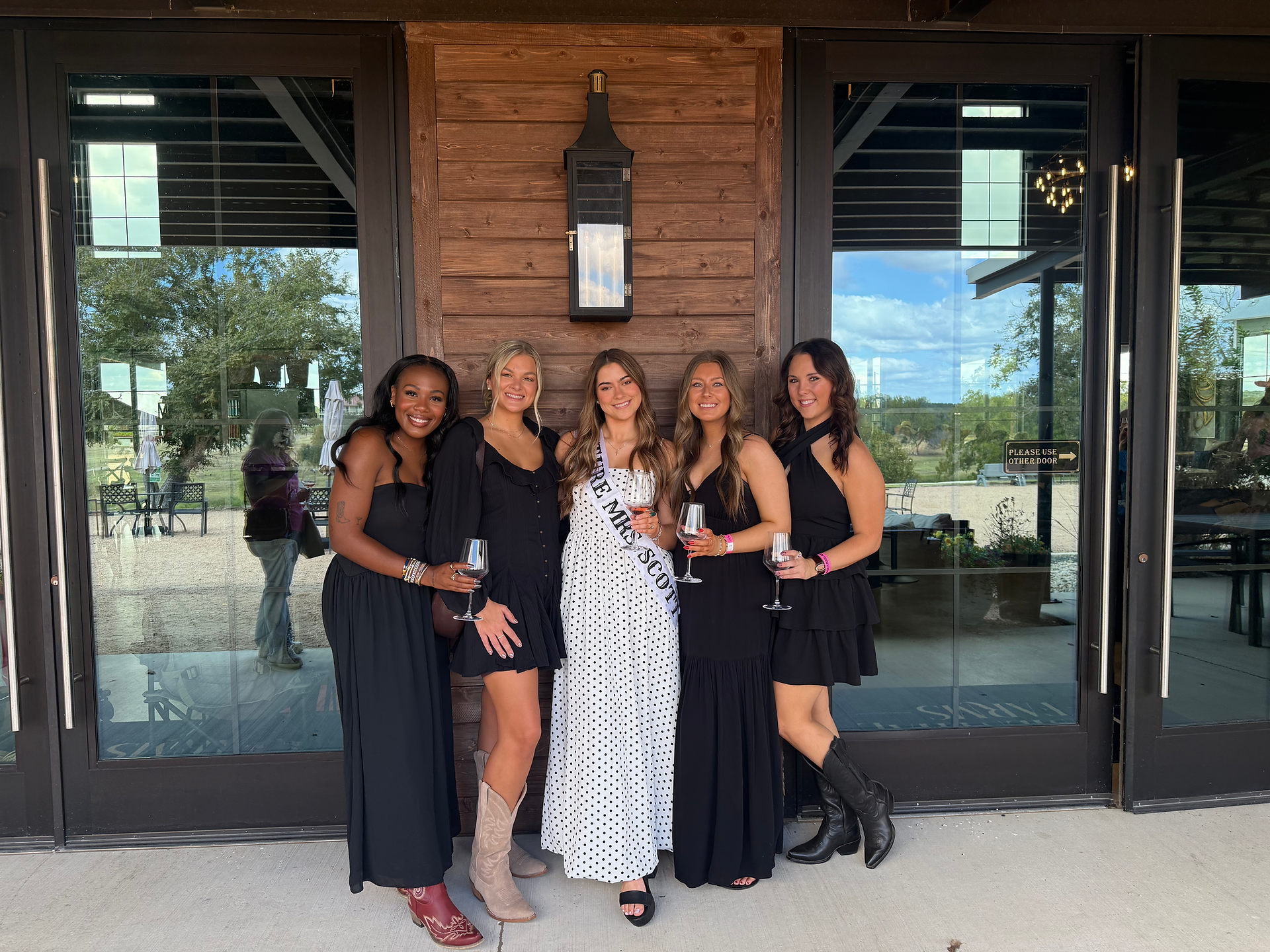 Group of friends smiling outside Blumenthal Winery in Fredericksburg, Texas during a girls’ weekend wine tour.