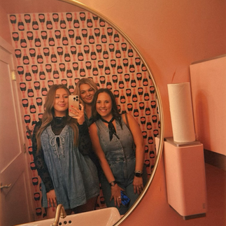 Friends taking a mirror selfie in the pink restroom at Brooke’s Bubble Bar in Fredericksburg.