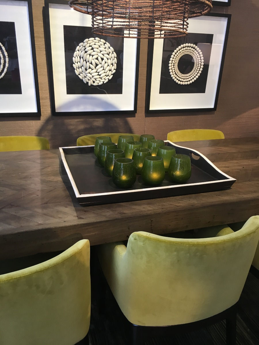 Timber dining table with green velvet chairs and black and white art on wall in room