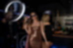 Woman in a sparkling dress poses with a peace sign at a party. She wears sunglasses, standing near a bar with a lit ring light on a 360 Video Booth. Energetic vibe. Supplied by 360 Photo Hire.