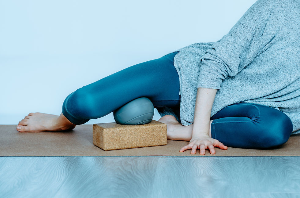 Practicing self myofascial release on the hip adductors with a yoga therapy ball and block for targeted muscle relief.