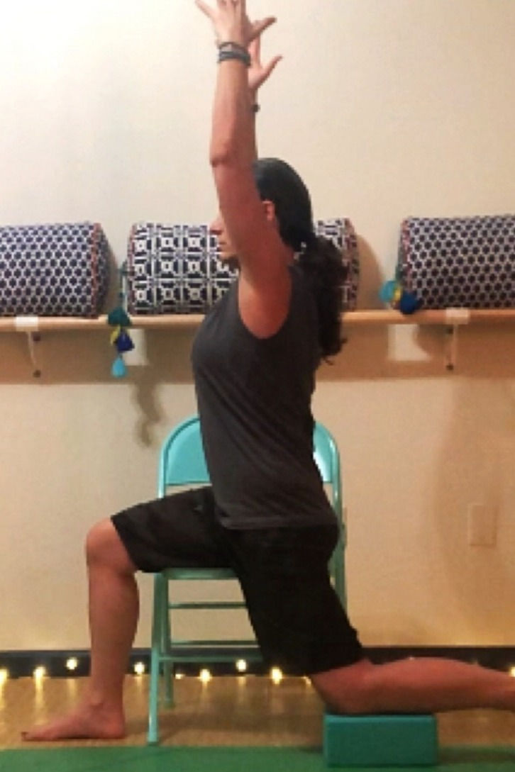 A dedicated older beginner practices yoga with the aid of a chair and blocks for a supportive and accessible experience.