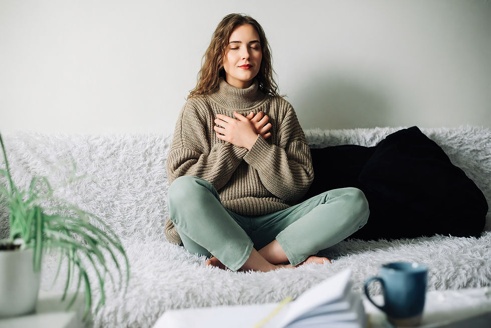 Middle-aged woman practicing mindfulness to interrupt the stress-response from a traumatic trigger - remembering the present moment, with her hands grounded into her heart and breathing.