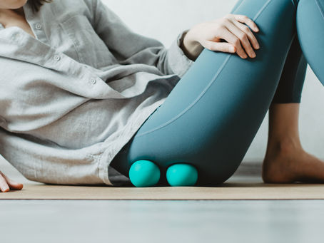 Woman practicing self-massage with two therapy balls targeting the fascia around the gluteus muscles of the hip with sinking pressure, calming the nervous system and improving local circulation.
