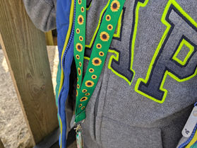 Hidden disability lanyard for autism, green with yellow sunflowers on it. 