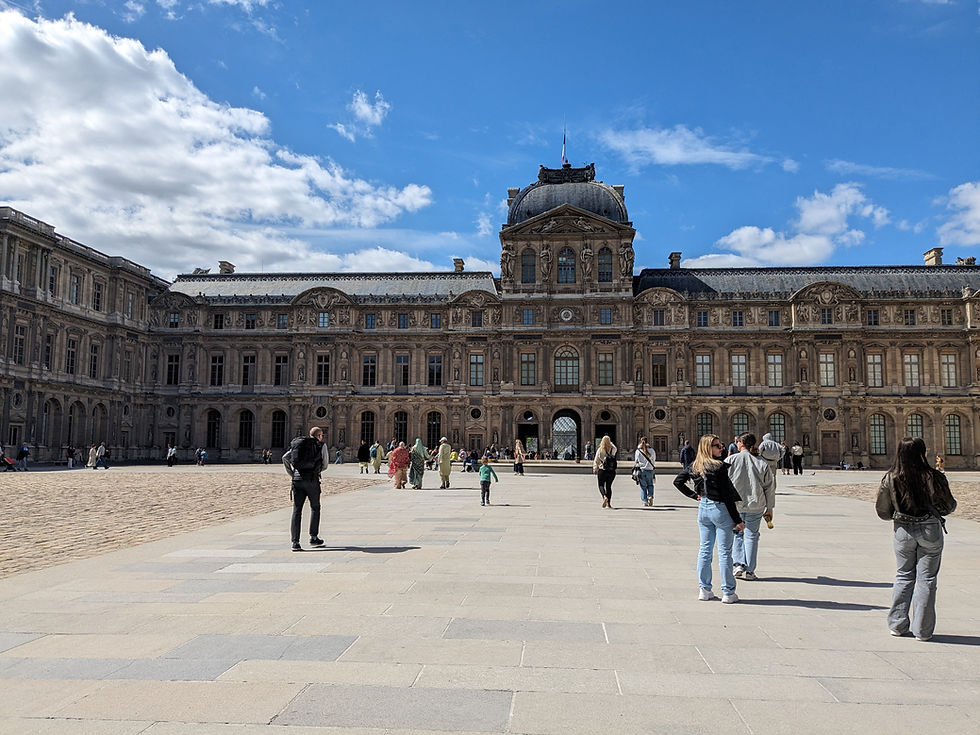 Palatial courtyard of Cour Caree, Paris. Features ornate buildings and clock tower about the entry arch.