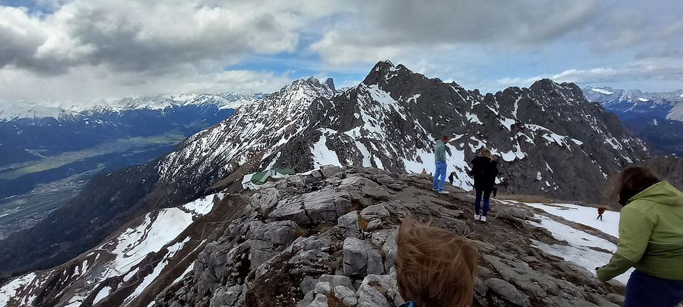 Nordekette, Top of Innsbruck Mountain peaks with people walking on rocky ground covered in snowy patches.