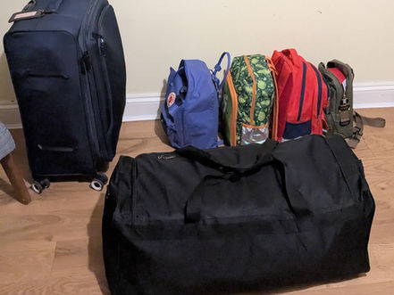 Four day packs and two family suitcases packed and ready to travel