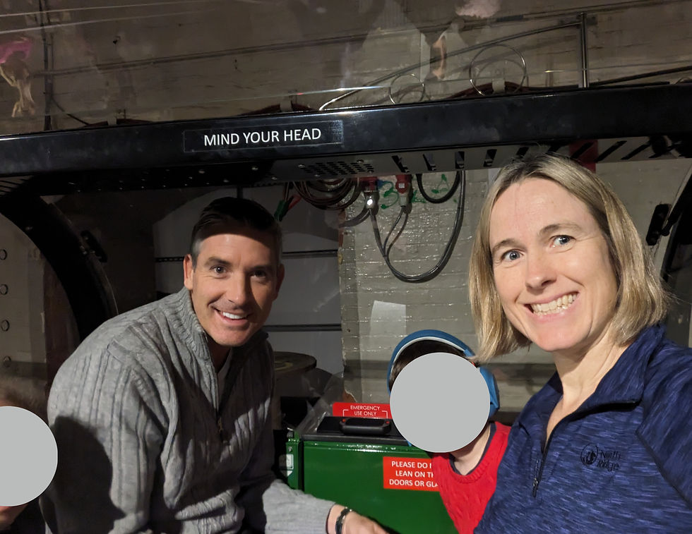 Two adults and two children (faces obscured) smiling from inside the mail rail ride carriage, waiting to depart.