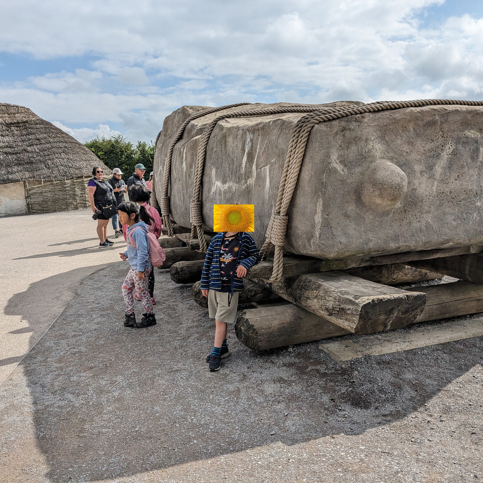 An autistic child leaning against the giant Sarsen Stone at Stonehenge. The rectangular stone is wrapped in thick ropes and rests on huge wooden beams.