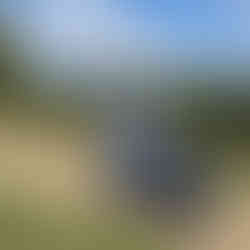 An older lady sitting on a tramper outdoor mobility scooter on a gravel path in the American Museum and Gardens