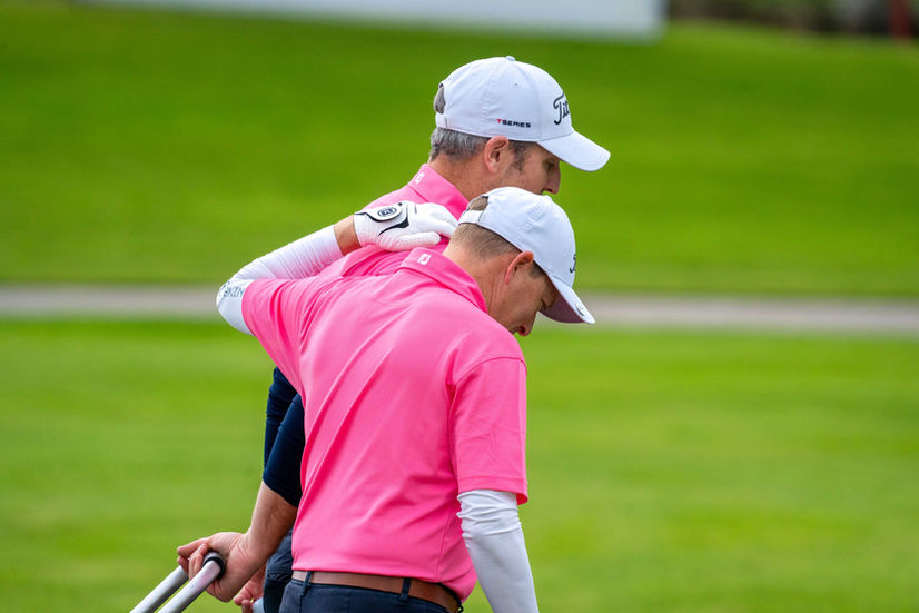 Two golfers walking, one in pink shirt