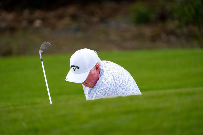 Golfer bending over, club beside him