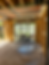 Sunlit construction site interior with wooden frames, glass doors opening to a garden. Ceiling scaffolding marked "BUILDSAFE." Calm atmosphere.
