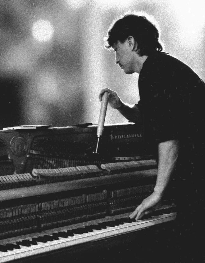 Profissional realizando afinação e regulagem de piano vertical.